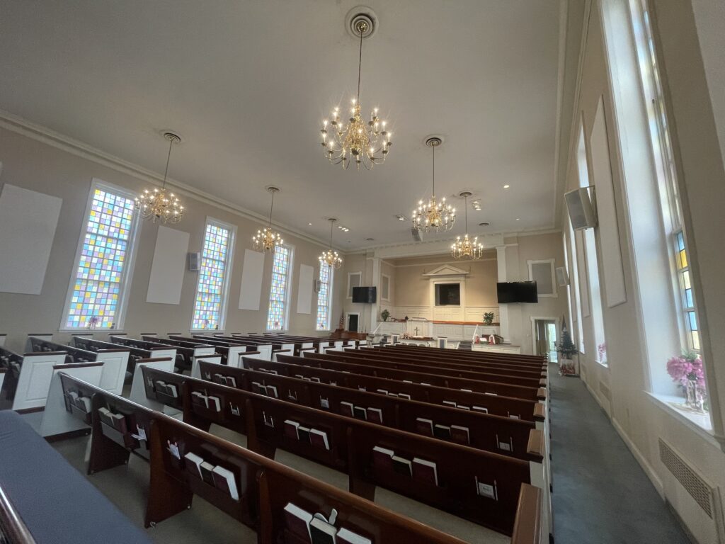 Interior of the Four Mile Creek sanctuary — pews, chandeliers, and stained glass