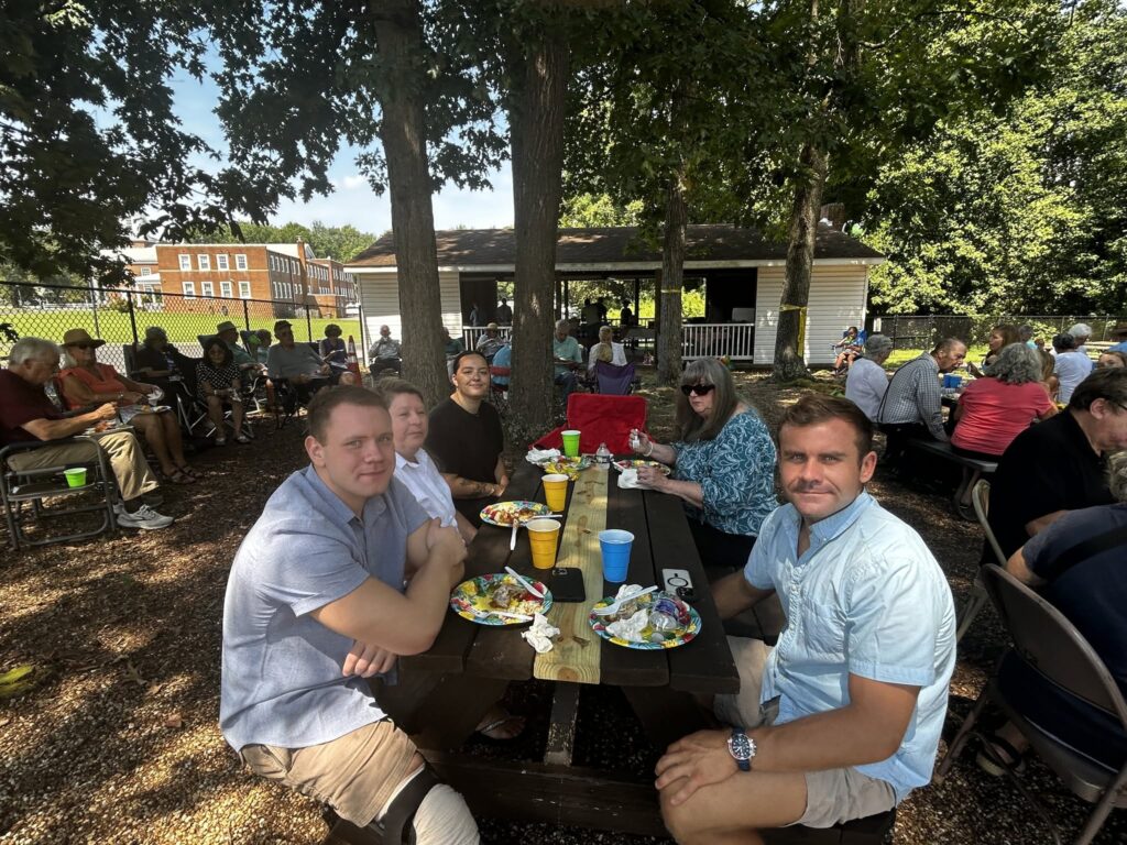Members and families sharing a meal at an outdoor church picnic